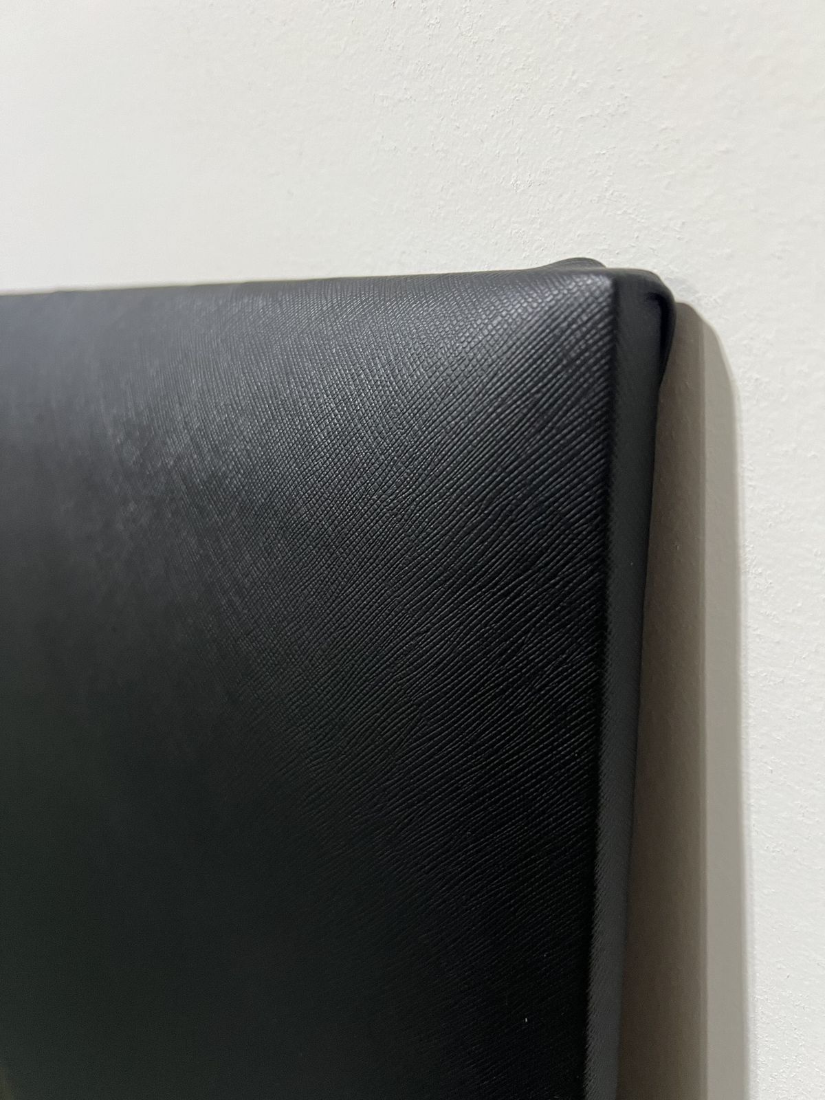 Close-up of cross-hatch embossed black vinyl texture on a Shank Pro wall panel